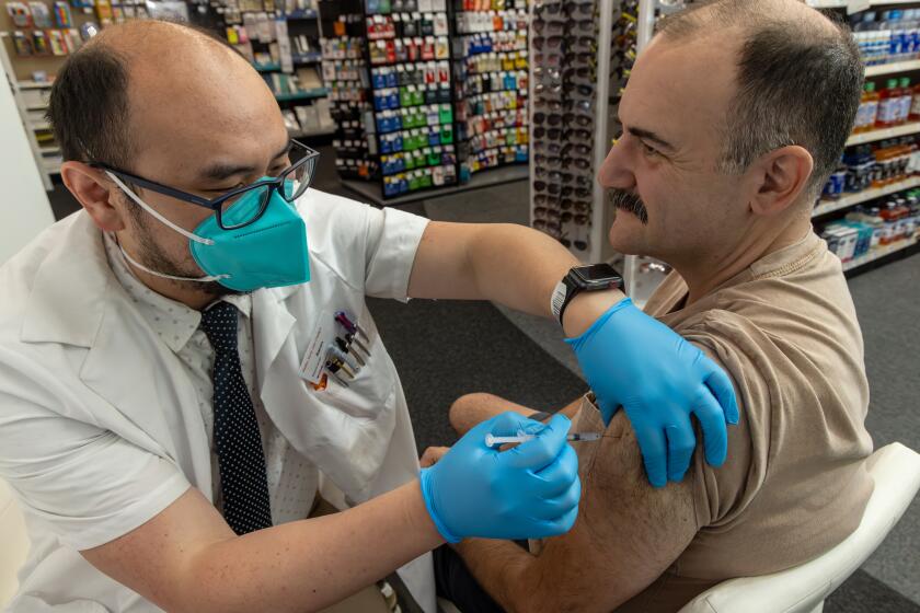 EAGLE ROCK, CA - SEPTEMBER 14: Pharmacist Aaron Sun administers new vaccine COMIRNATY® (COVID-19 Vaccine, mRNA) by Pfizer, to Jimmy Smagula at CVS Pharmacy in Eagle Rock, CA. (Irfan Khan / Los Angeles Times)