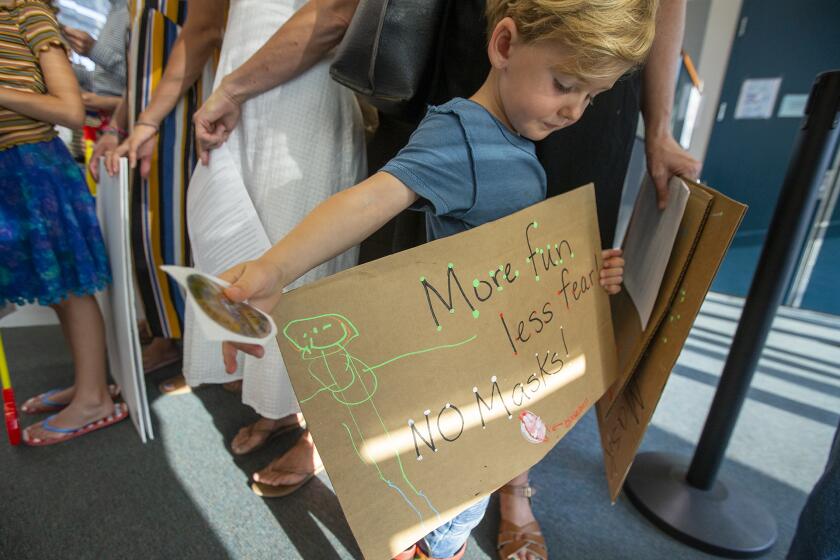 Ames Delle, 4, holds a sign promoting no masks for school children during a rally under the broader national "Let Them Breathe" movement before Newport Mesa Unified School District's regular board meeting on Tuesday, August 17.