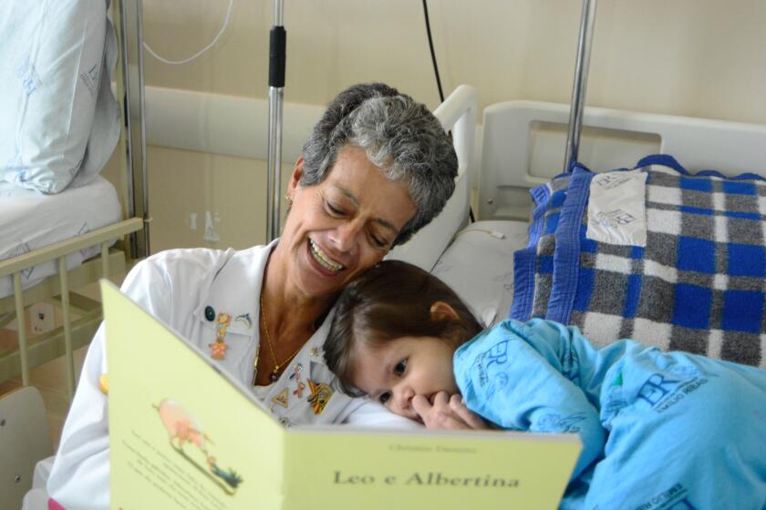 A storyteller reads to a young ICU patient. 