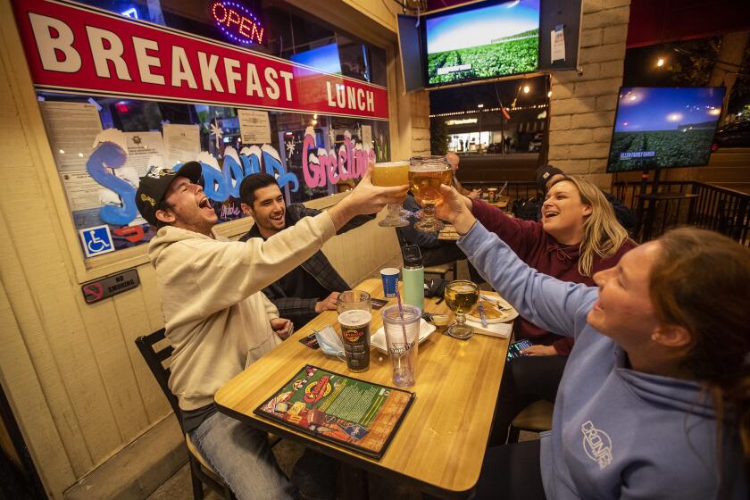 AGOURA HILLS, CA - DECEMBER 07,2020: left to right-friends Connley Peterson, Garrett Lambert, Erin Mazza, and Teresa Frase, toast each other while singing along to "Proud to be an American" at Cronies sports bar and grill in Agoura Hills. The sports bar defied the shut down order by the state. (Mel Melcon / Los Angeles Times)