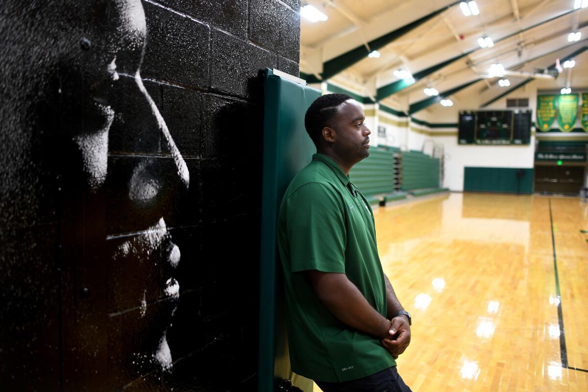 St. Vincent-St. Mary High athletic director Willie McGee stands next to a mural of LeBron James, his childhood friend and high school teammate.