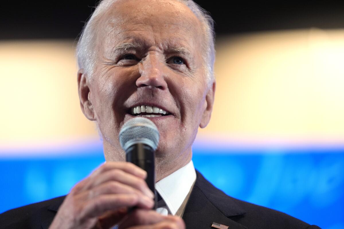 A closeup of President Biden holding a microphone and speaking