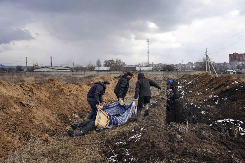 Dead bodies are put into a mass grave on the outskirts of Mariupol, Ukraine, Wednesday, March 9, 2022, as people cannot bury their loved ones because of the heavy shelling by Russian forces. (AP Photo/Evgeniy Maloletka)