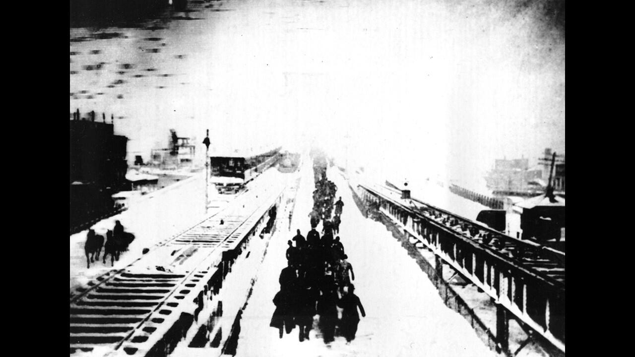 New Yorkers hike across a bridge after being forced to leave their train when it stalled as a result of the heavy snow during the blizzard of 1888.