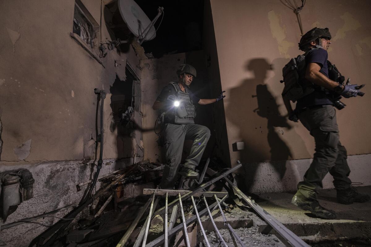 Two men navigate debris inside a damaged home 