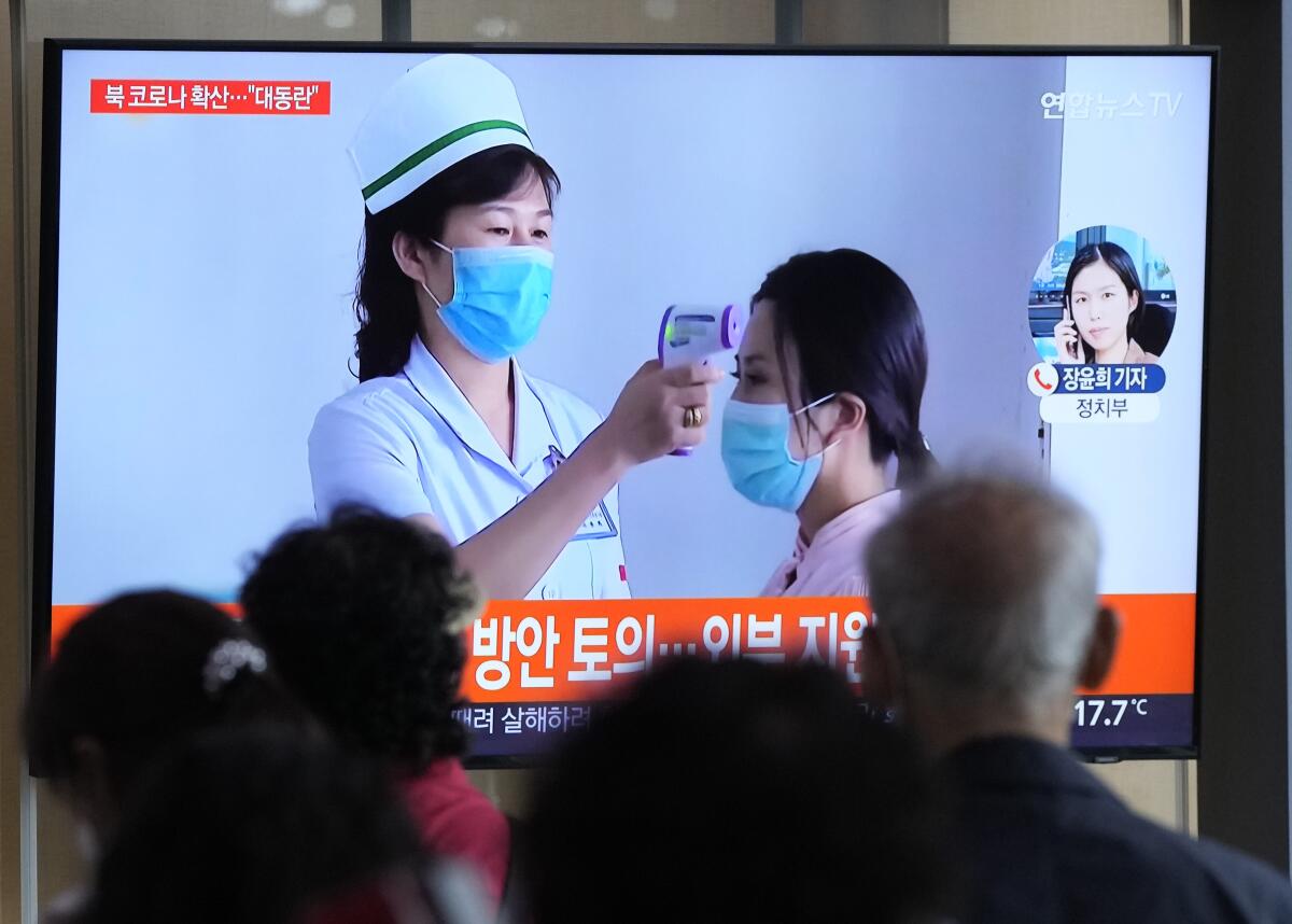 A TV screen shows a nurse using a handheld thermometer to assess a patient. 