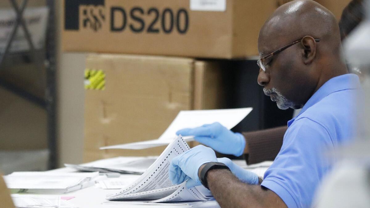 An employee at the Broward County Supervisor of Elections office examines ballots on Nov. 14.