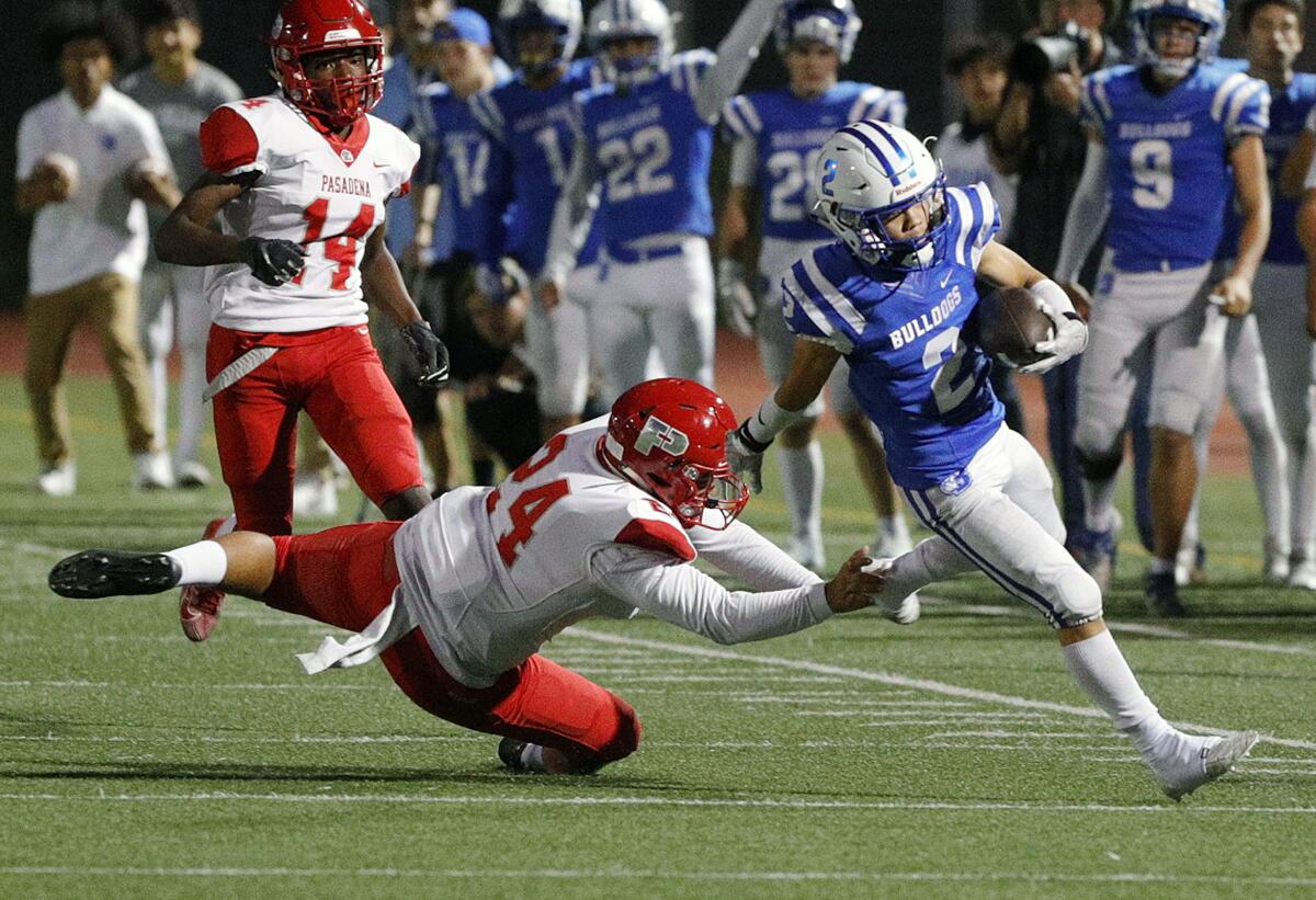 Burbank's Vincent Vang nearly evades the diving tackle of Pasadena's Fernando Simental on a long kickoff return in a Pacific League football game at Memorial Field in Burbank on Tuesday, September 26, 2019.