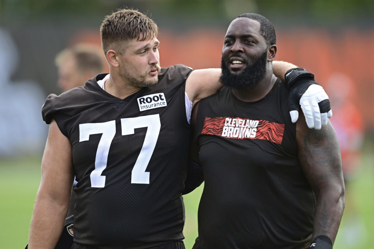 Cleveland Browns guard Wyatt Teller, left, and offensive tackle Chris Hubbard walk off the field after an NFL football practice in Berea, Ohio, Friday, July 29, 2022. (AP Photo/David Dermer)