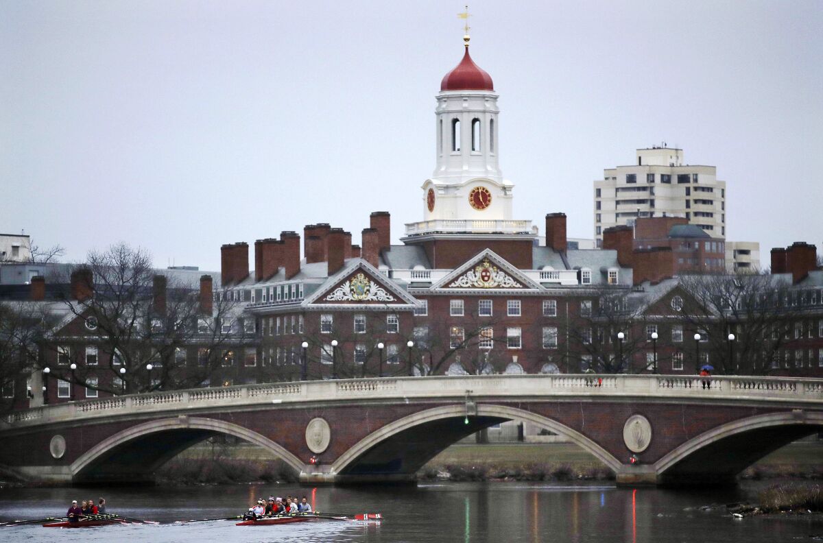 FILE - In this March 7, 2017, file photo, rowers paddle along the Charles River past the Harvard University campus in Cambridge, Mass. Harvard University will divest itself from holdings in fossil fuels. President Lawrence Bacow said Thursday, Sept. 9, 2021, that the university has legacy investments in a number of private equity funds with holdings in the fossil fuel industry and those indirect investments constitute less than 2% of the endowment. (AP Photo/Charles Krupa, File)