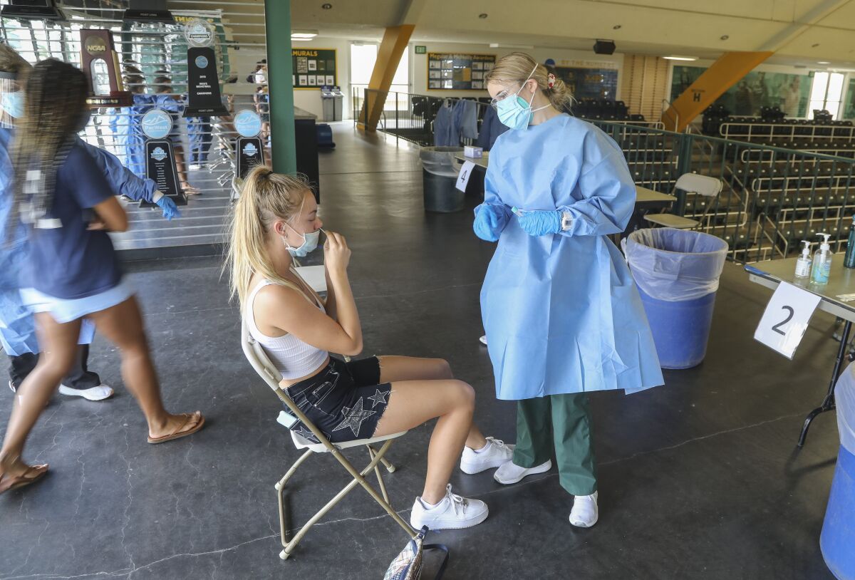Point Loma Nazarene student Ellie Turk (left) gets a COVID-19 test in the school gym from Nicole Orth