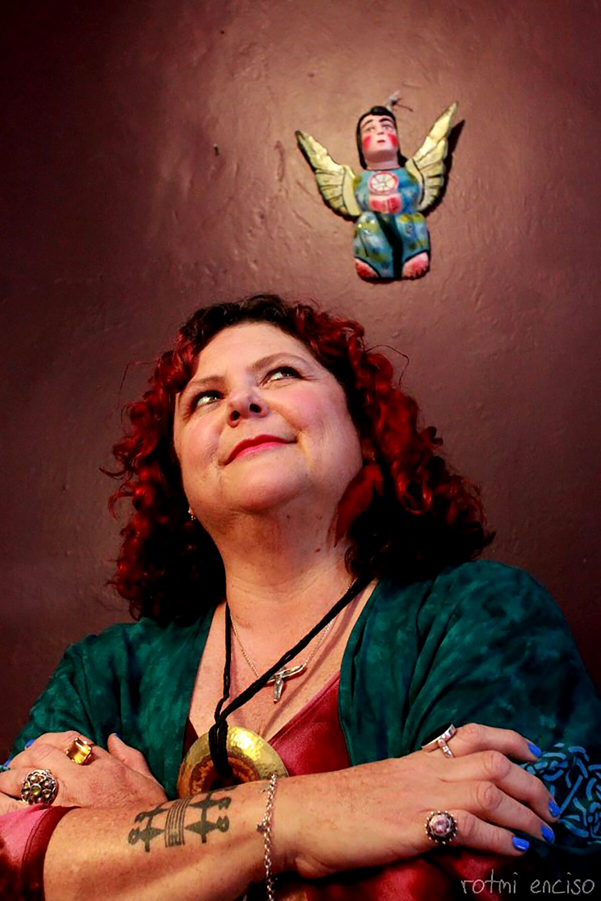 A portrait of tatiana de la tierra with a terra cotta angel hovering on the wall behind her.