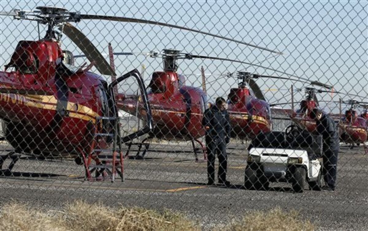 Mechanics work on a grounded Sundance tour helicopter on the tarmac at McCarran International Airport Thursday, Dec. 8, 2011, in Las Vegas. A Sundance tour helicopter crashed killing the pilot and four passengers on Dec. 7. (AP Photo/Isaac Brekken)