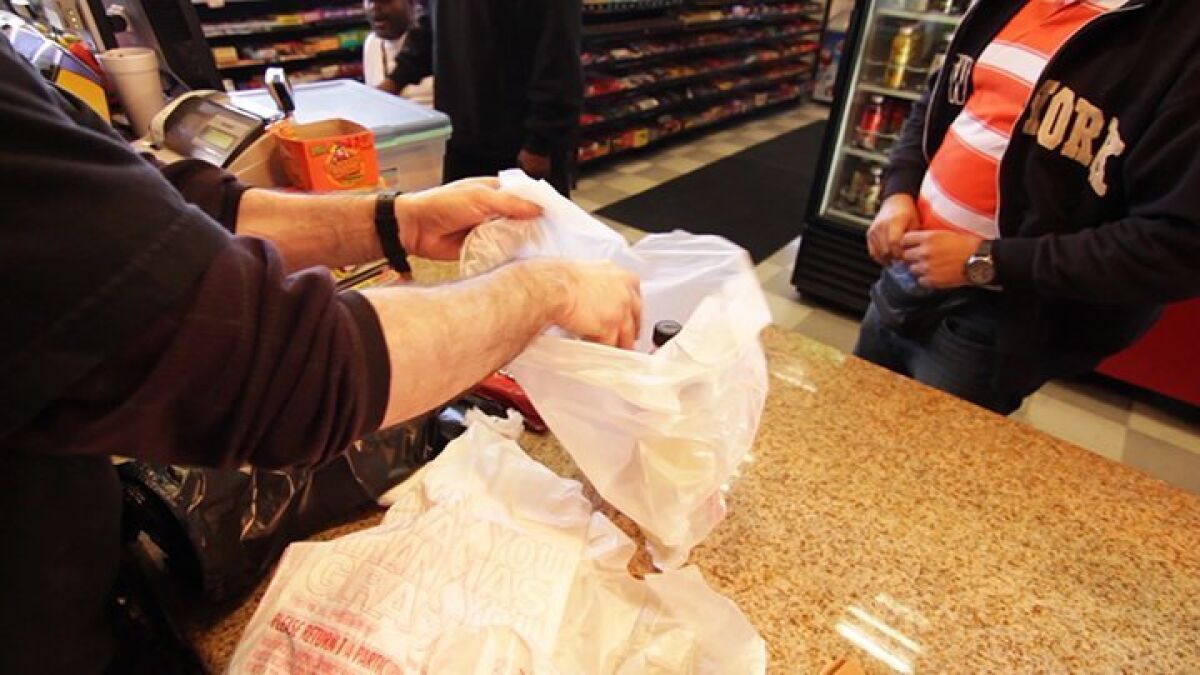 A customer in San Diego receives purchased items in a plastic bag.