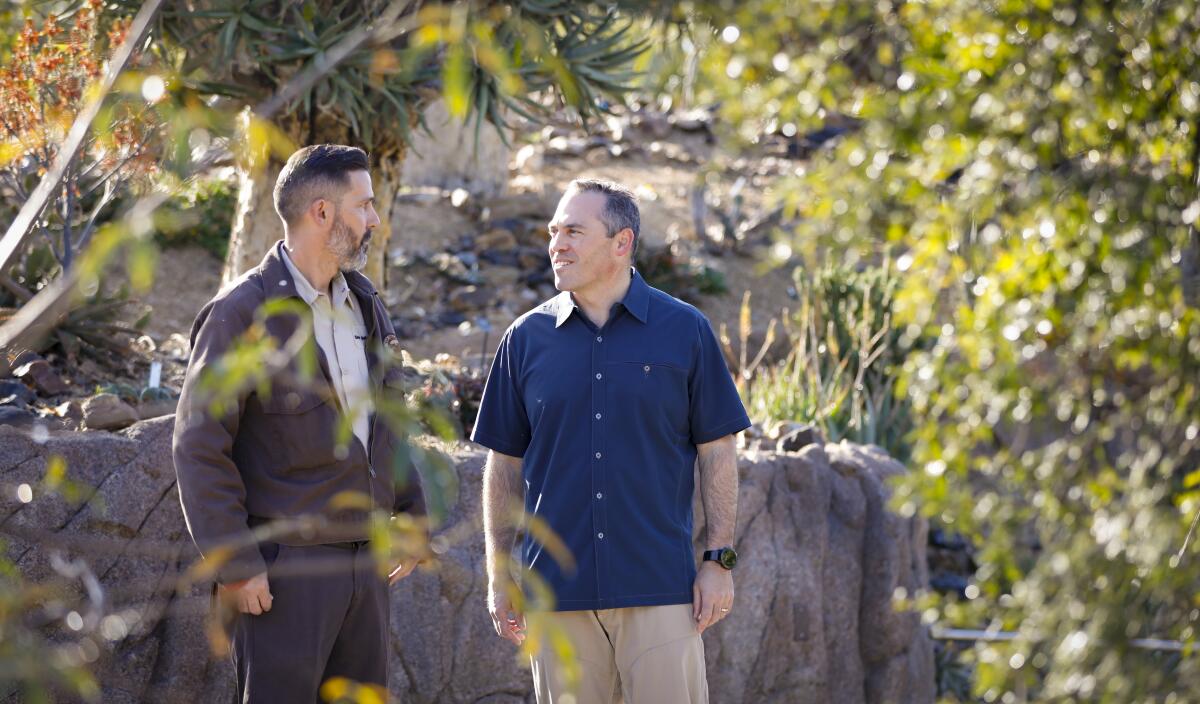 Patrick Smith, senior horticulturalist at the San Diego Zoo, left, gives Paul Baribault, the new president and CEO of San Diego Zoo Global, a tour of the African Garden section in the Africa Rocks exhibit at the zoo on Tuesday.