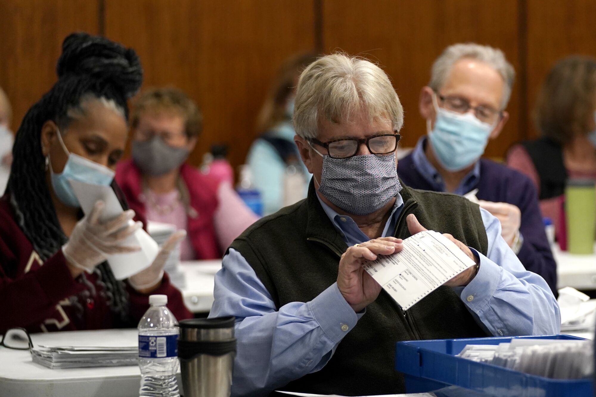 An election worker inspects a mail-in ballot before it's counted in Harrisburg, Pa., on Nov. 3.