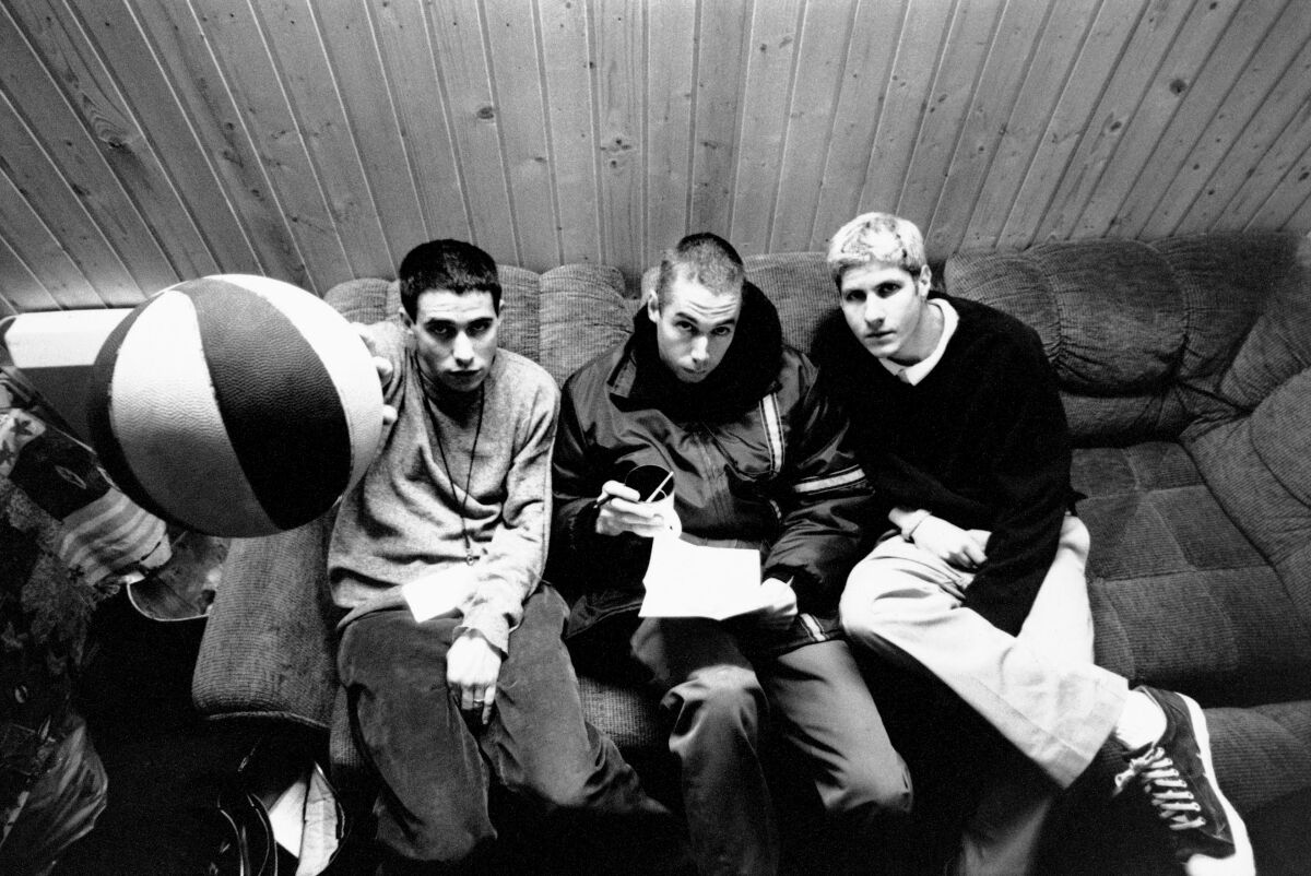 Three men sitting on a couch, looking up.