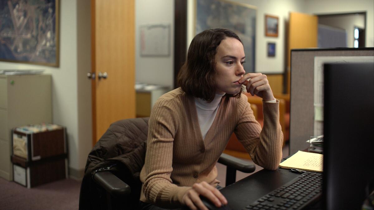 A woman leans over her desk toward her computer.