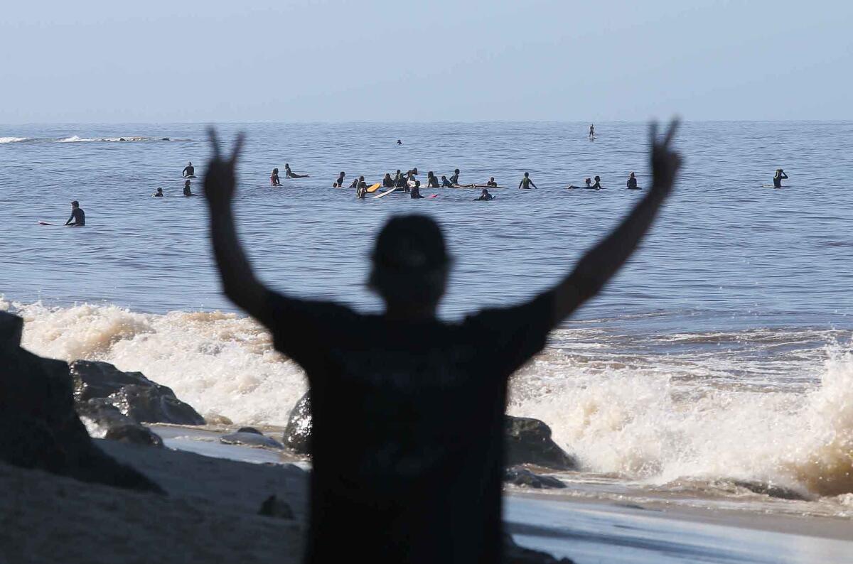 Someone gives a peace sign to surfers in Laguna Beach on Tuesday.