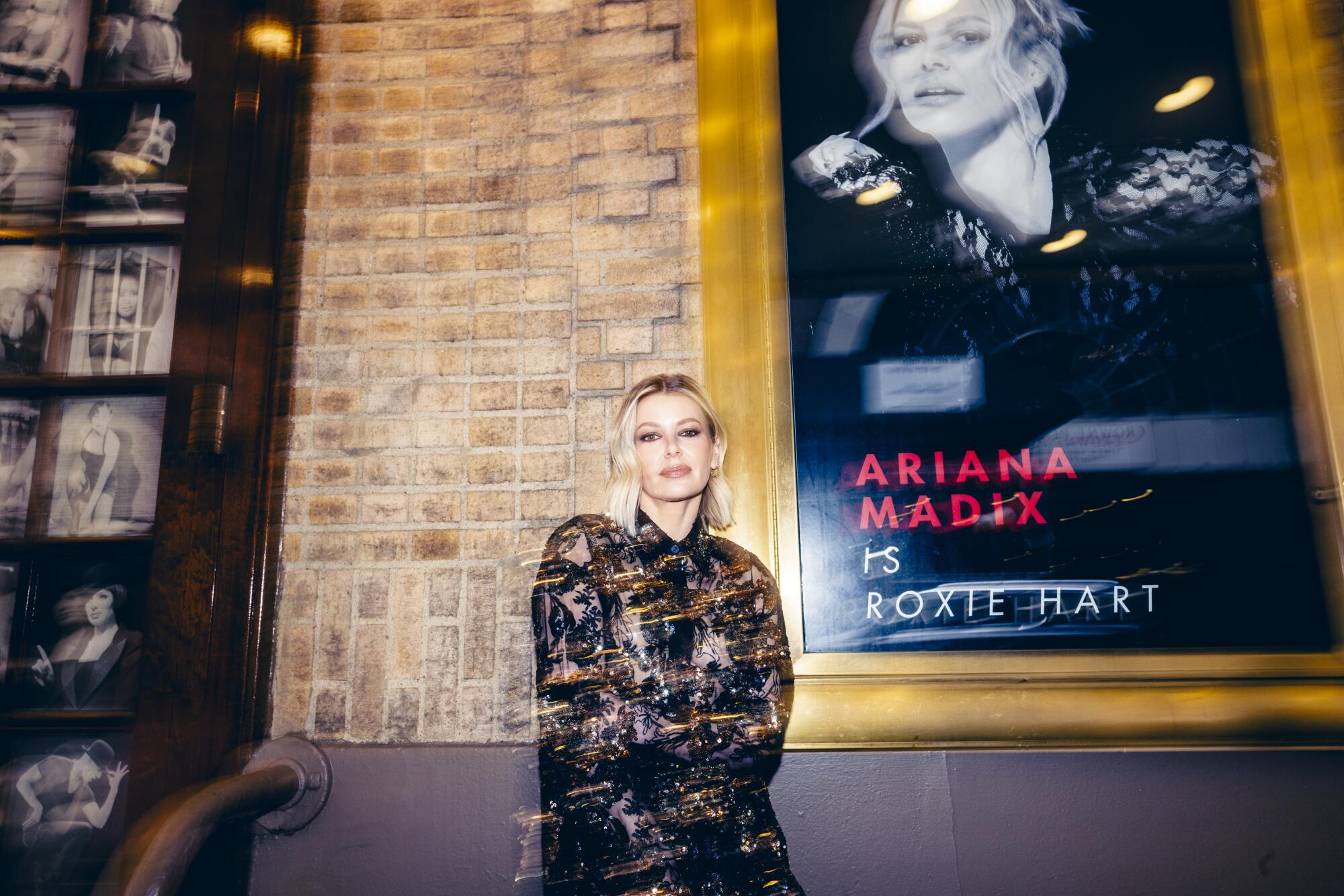Ariana Madix stands next to a poster advertising her as Roxie Hart in "Chicago" at Broadway's Ambassador Theater