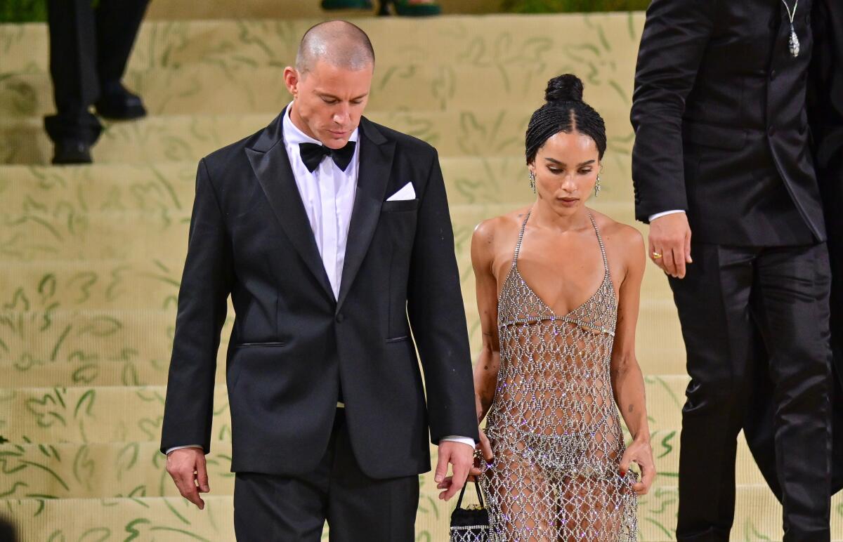 Channing Tatum in a tuxedo walking down golden stairs next to Zoê Kravitz in a sheer net gown
