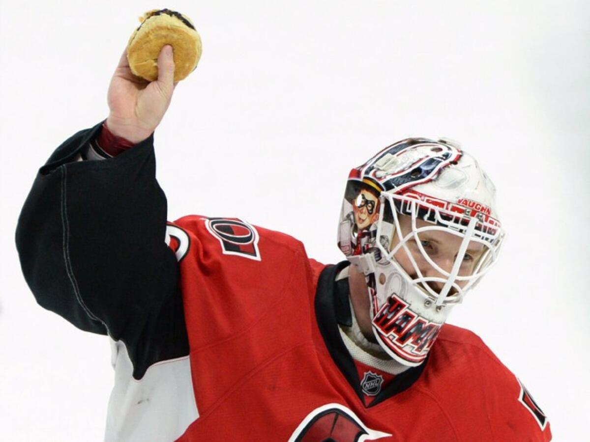 Senators goalie Andrew Hammond, nicknamed 'Hamburglar', holds up a hamburger that was thrown on the ice after a Senators' shootout victory.