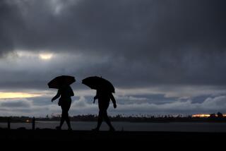 People walk along Mission Bay in a light rain as a storm moved into the area on Monday, November 7, 2022 in San Diego, CA.