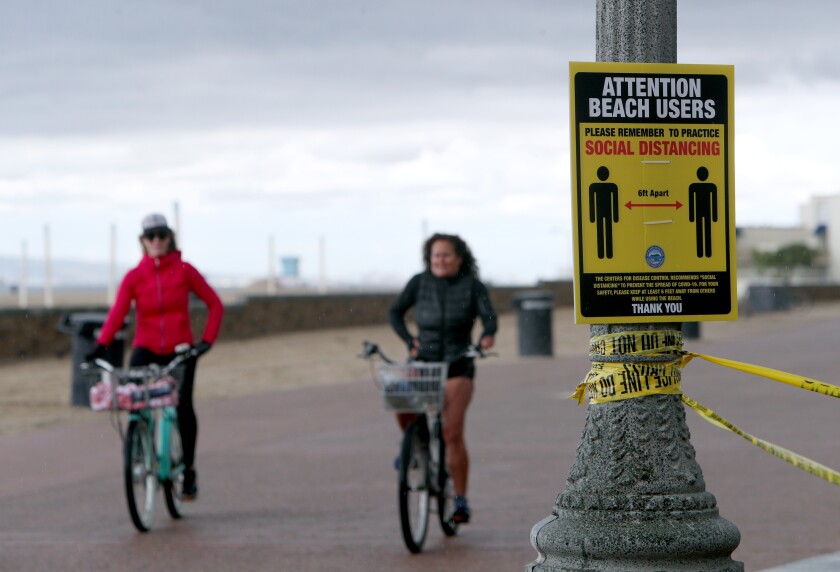 Bicycle riders practice social distancing just north of the Huntington Beach pier, in Huntington Beach on April 10.