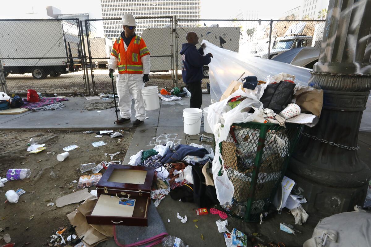 Sanitation workers clean up a homeless encampment on 1st Street just west of City Hall.