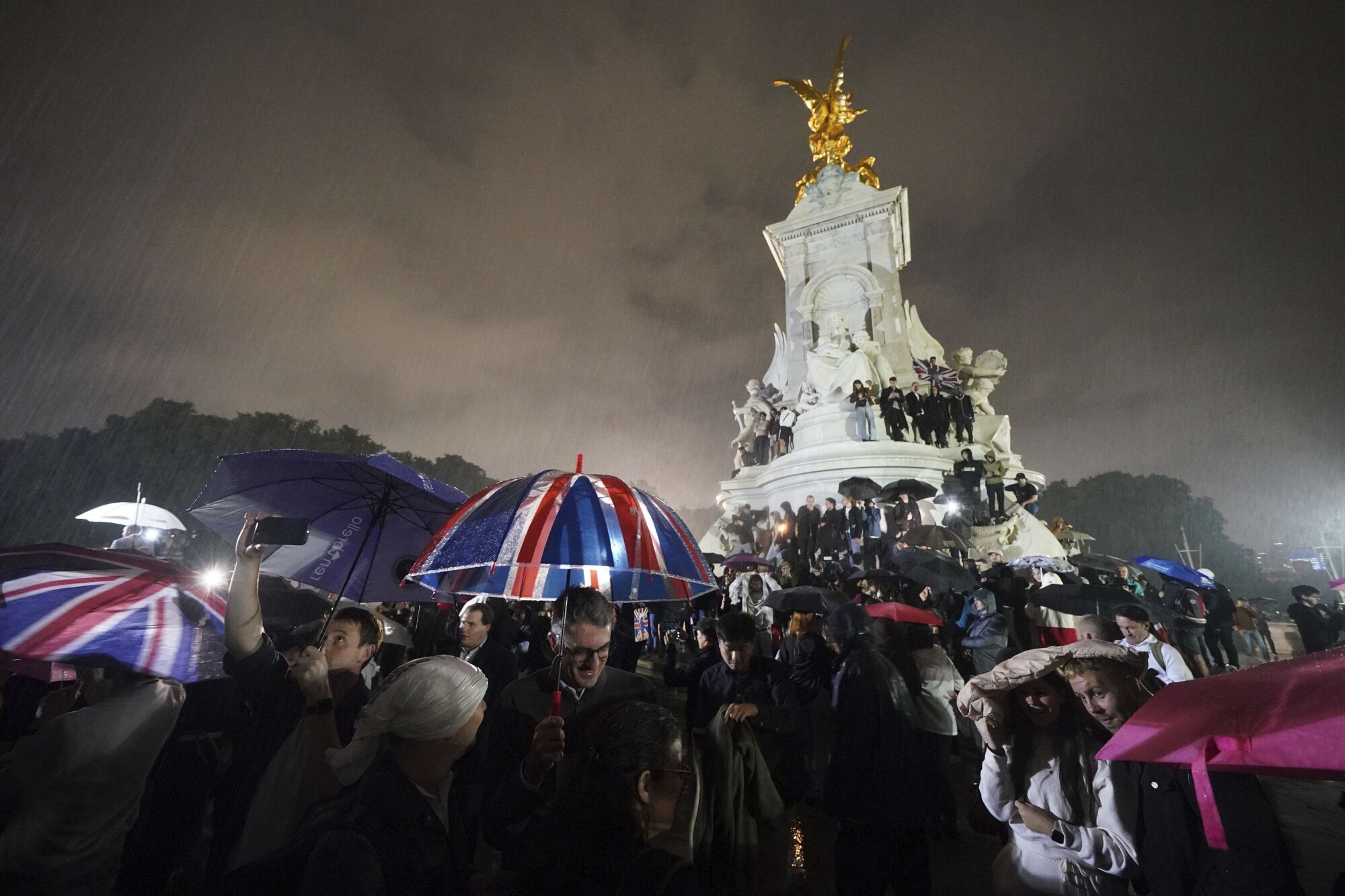 People gather at the Queen Victoria Memorial in front of Buckingham Palace