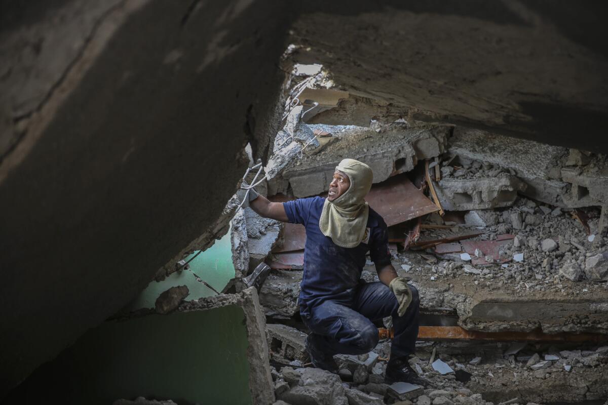 A firefighter searches for survivors inside a damaged building.