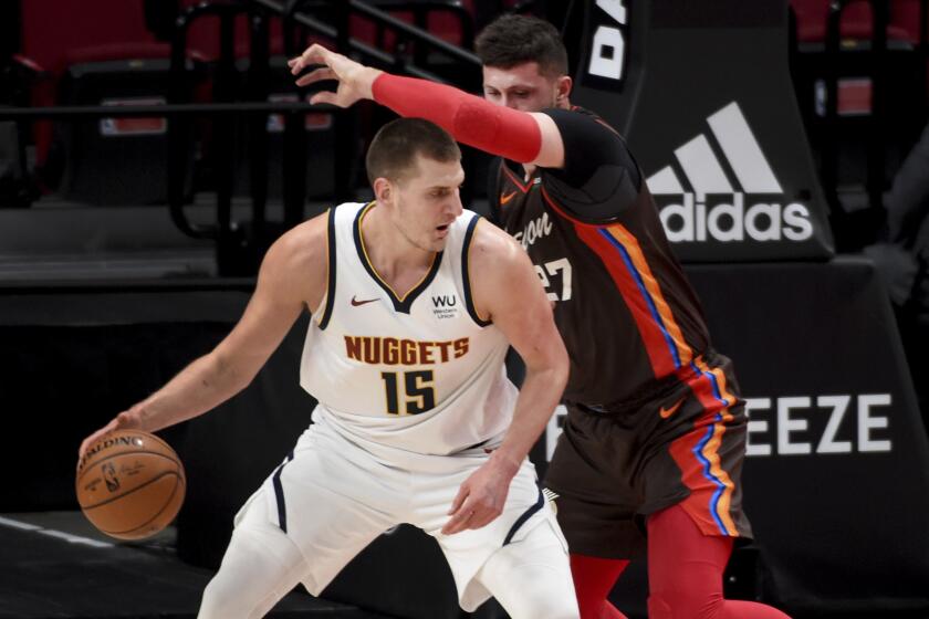 Denver Nuggets center Nikola Jokic, left dribbles the ball on Portland Trail Blazers center Jusuf Nurkic, right, during the first half of an NBA basketball game in Portland, Ore., Sunday, May 16, 2021. (AP Photo/Steve Dykes)