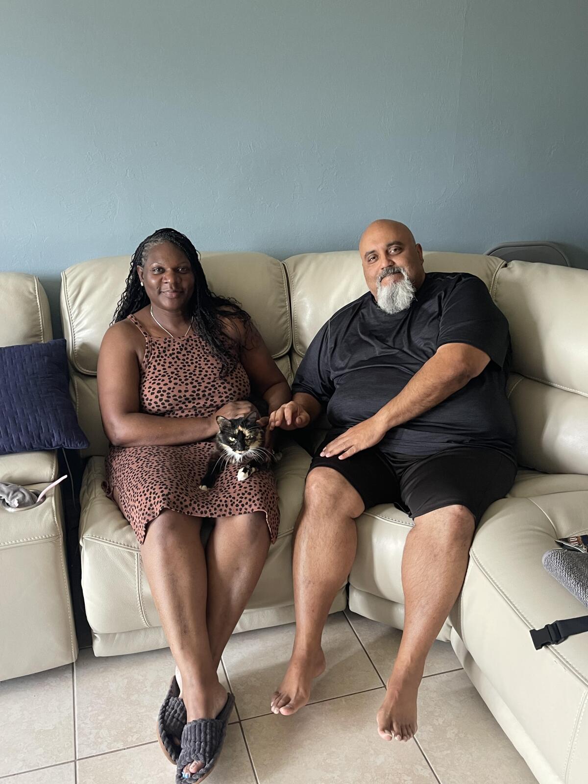 Sherrie, left, and Alfonso Meletiche sit on the couch, while family cat, Baby, takes a rest.