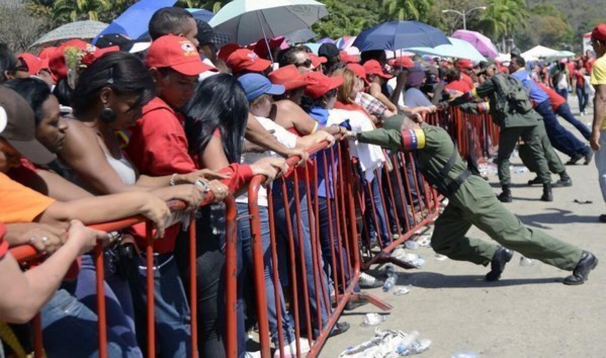 Venezuelan soldiers brace against protective fences as supporters wait in line to pay last respects to the late Venezuelan President Hugo Chavez outside the Military Academy in Caracas.