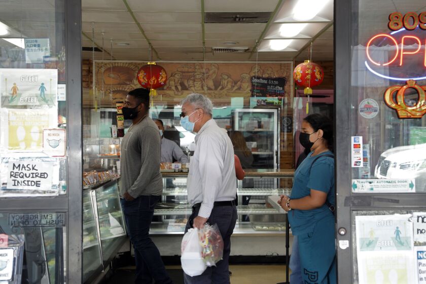LOS ANGELES, CA - MARCH 13: Customers wear masks inside a bakery in Chinatown on Sunday, March 13, 2022. As the Omicron surge continues to wane, Los Angeles County has been lifting COVID-19 mandates including indoor masking and vaccine verification in certain settings. (Myung J. Chun / Los Angeles Times)