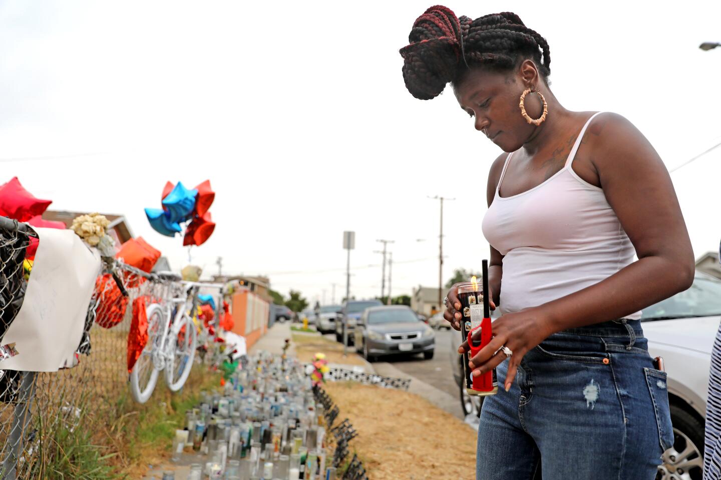 Rima Williams, cousin of Dijon Kizzee, on Tuesday places a lighted candle at the memorial where Kizzee was shot