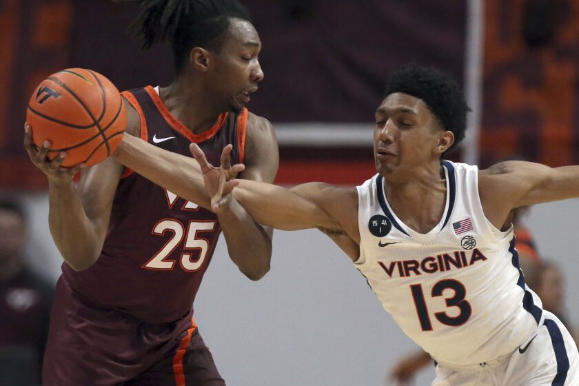 Virginia Tech's Justyn Mutts (25) has the ball tipped from him by Virginia's Ryan Dunn (13) i in the first half of an NCAA college basketball game in Blacksburg Va., Saturday, Feb. 4, 2023. (Matt Gentry/The Roanoke Times via AP)