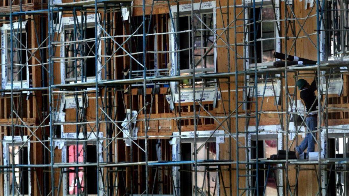 A worker stands on scaffolding at a construction site in Chinatown.