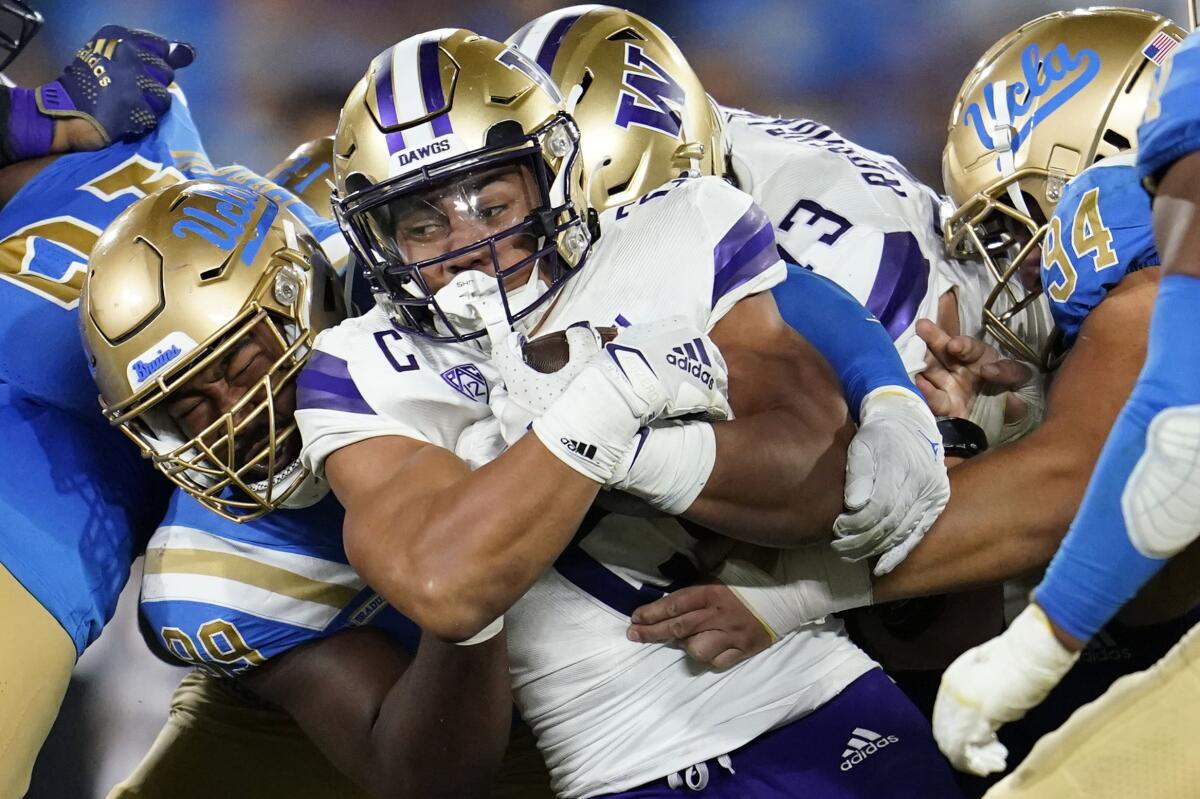 Washington running back Wayne Taulapapa is tackled by UCLA defensive lineman Jacob Sykes.