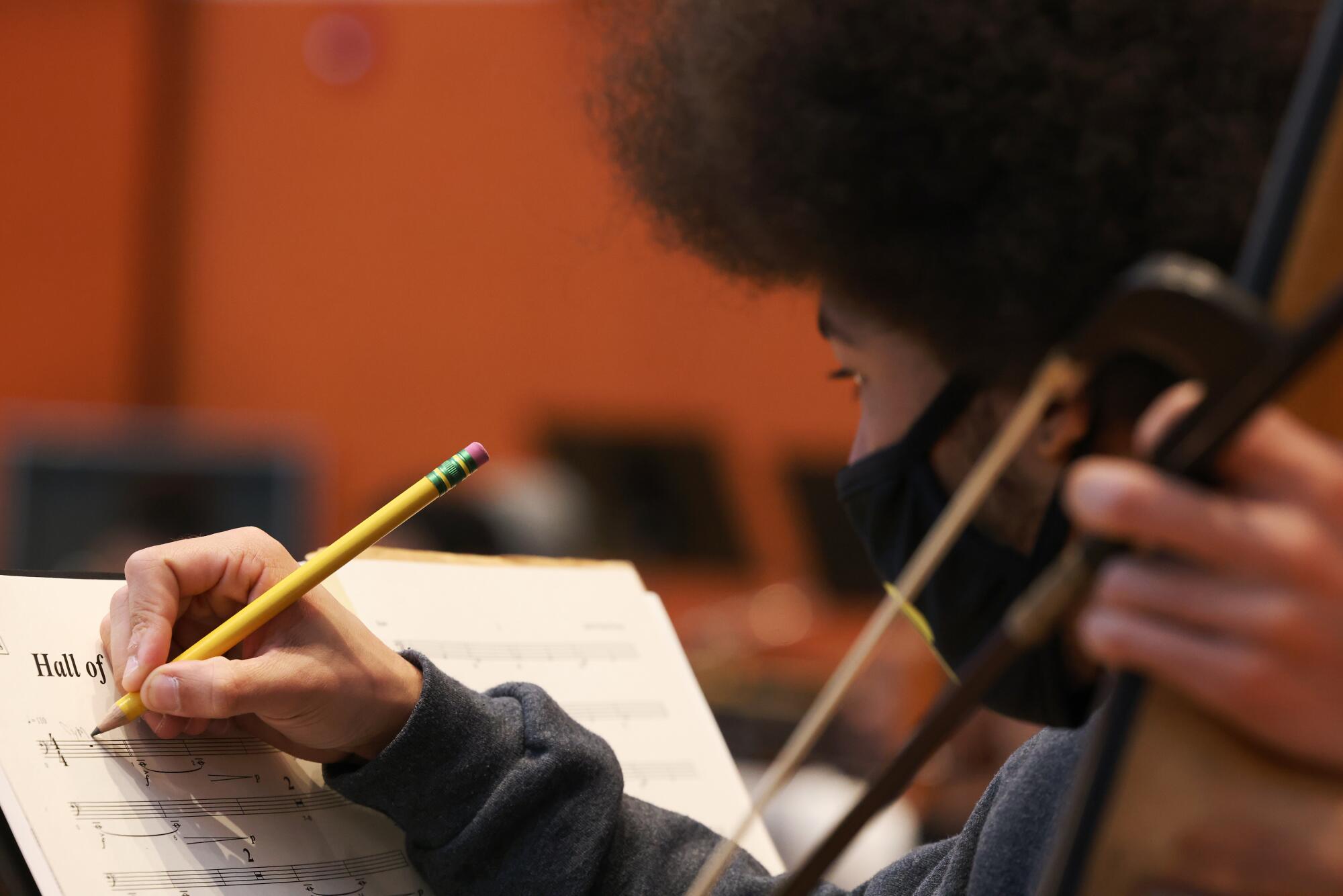 A member of the orchestra marks sheet music.