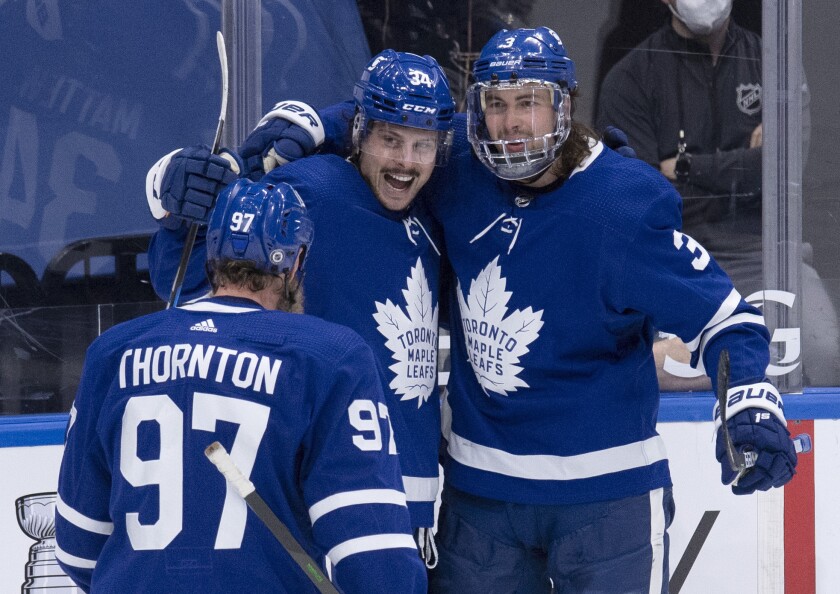 Toronto Maple Leafs center Auston Matthews (34) celebrates his 40th goal of the season with teammates Joe Thornton (97) and Justin Holl (3), during the third period of an NHL hockey game against the Montreal Canadiens on Thursday, May, 6, 2021, in Toronto. (Frank Gunn/The Canadian Press via AP)