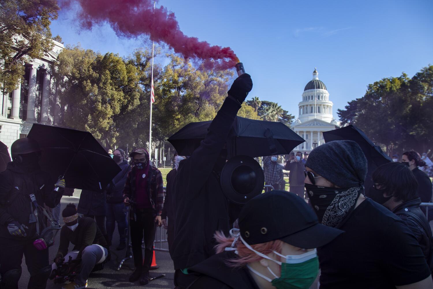 SACRAMENTO, CA - JANUARY 20, 2021: An ANTIFA protester sprays pink smoke during a demonstration near the California State Capitol on what was otherwise a quiet Inauguration Day on January 20, 2021 in Sacramento, California. The group is anti-cops, anti-right-wing and anti-presidents.(Gina Ferazzi / Los Angeles Times)