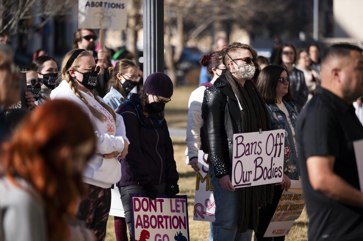 A group of protesters outside, some carrying homemade abortion rights signs with messages including "Bans off our bodies." 