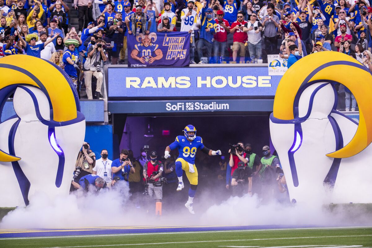 Rams fans cheer as Rams defensive lineman Aaron Donald leaps in the air while taking the field.