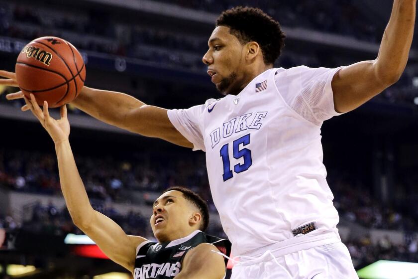 Duke center Jahlil Okafor tries to block a shot by Michigan State guard Travis Trice last week.