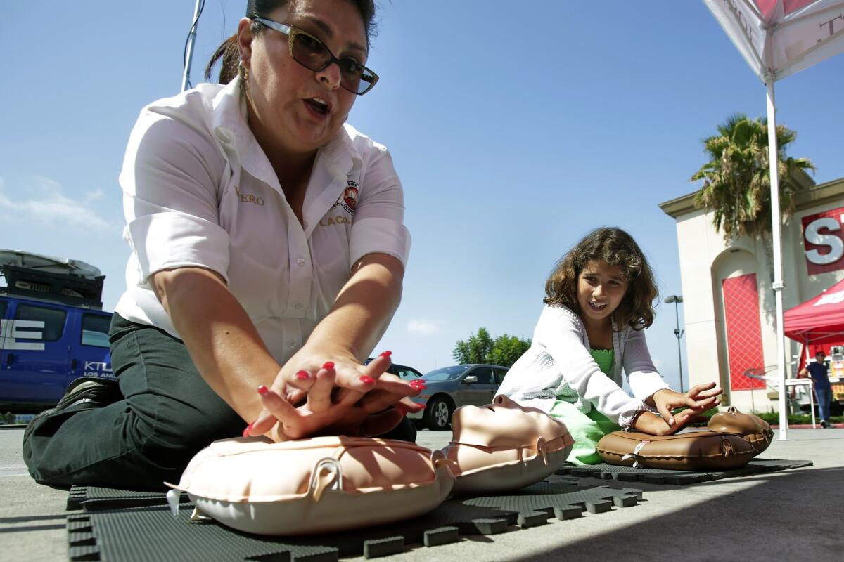 Los Angeles County Fire community services representative Rosemary Vivero, left, shows 9-year-old Francesca Krikorian how to perform CPR at the launch of PulsePoint Wednesday. PulsePoint is a free mobile app that alerts registered users whenever a cardiac arrest occurs in a public place nearby.