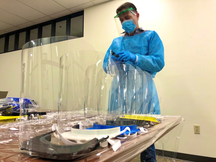 A Scripps Hospital employee assembles donated face shields.