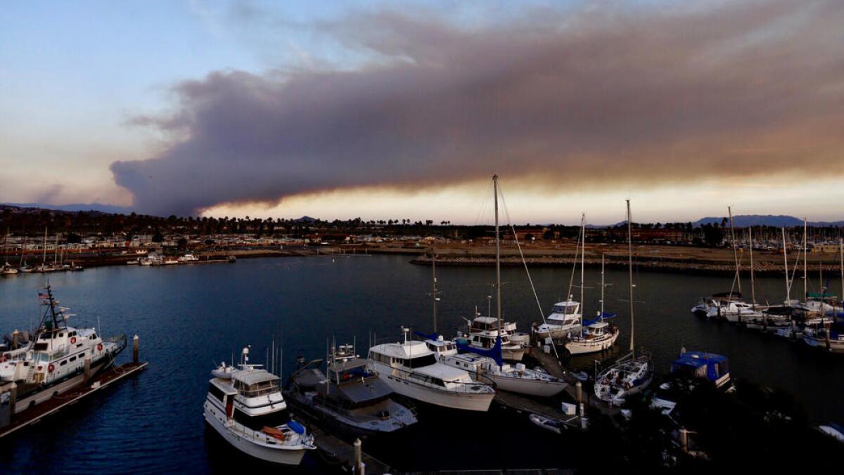 Smoke rises from the Thomas fire over the Ventura Harbor at sunset.