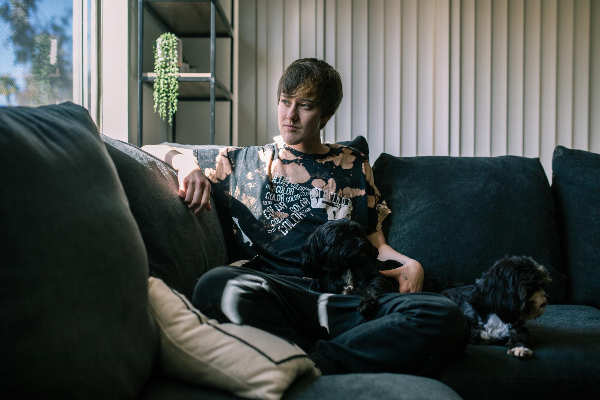 Raegan Fingles sits on a couch with his pets.