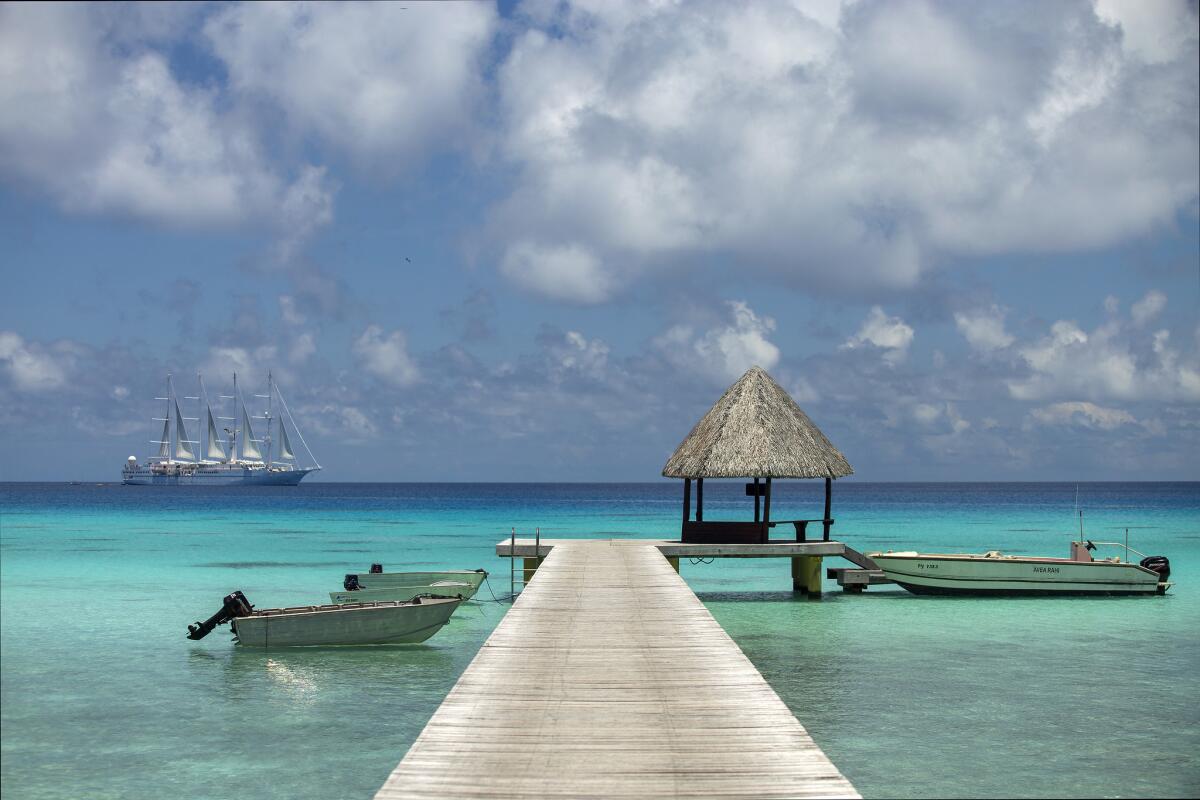 Boats are parked at Hotel Kia Ora's private dock in Rangiroa, French Polynesia. In the distance is Wind Spirit, one of Windstar Cruises' ships.